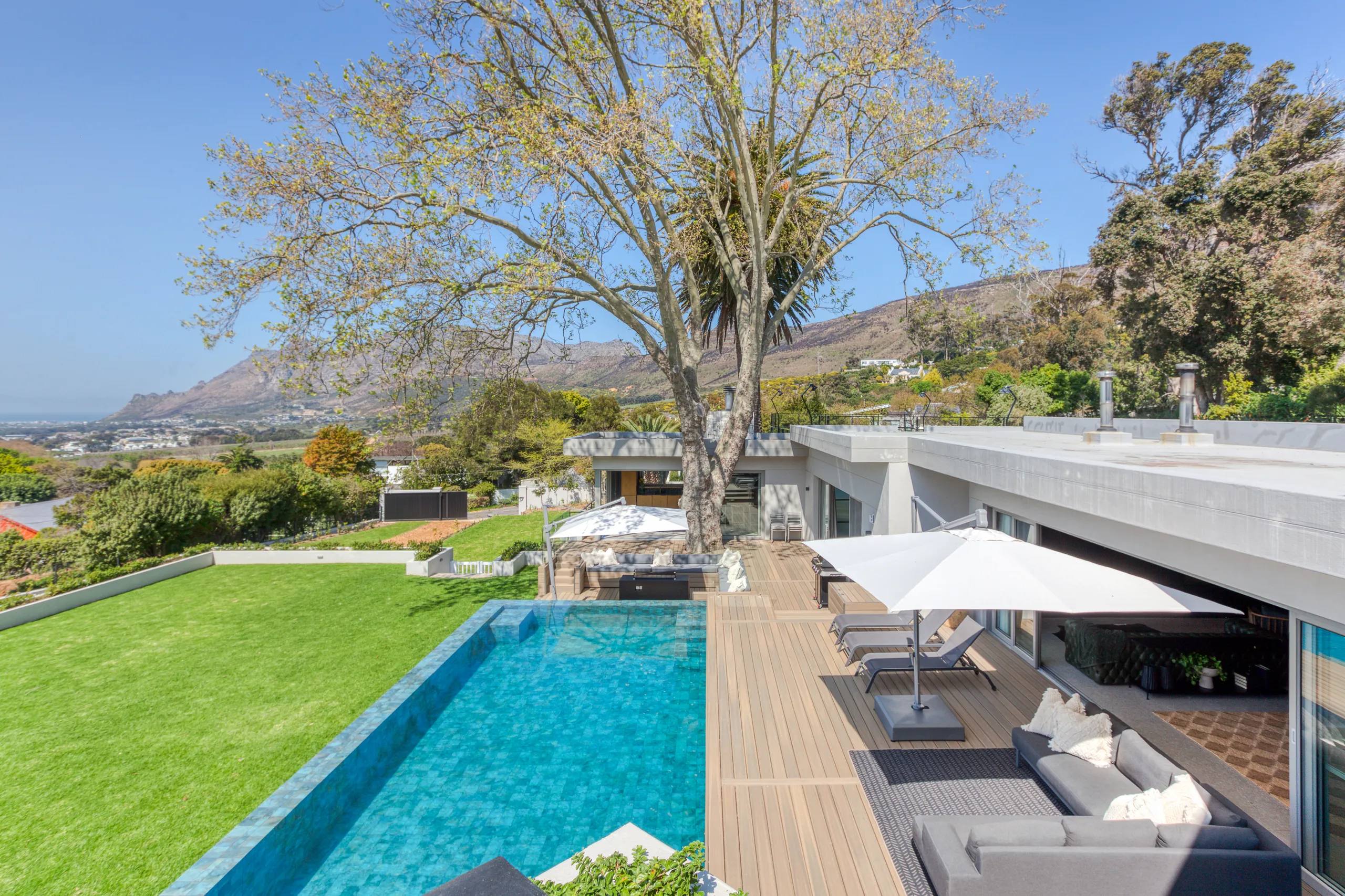 Zwaanswyk by Devbark — lawn and swimming pool beside a contemporary home, with mountain views beyond
